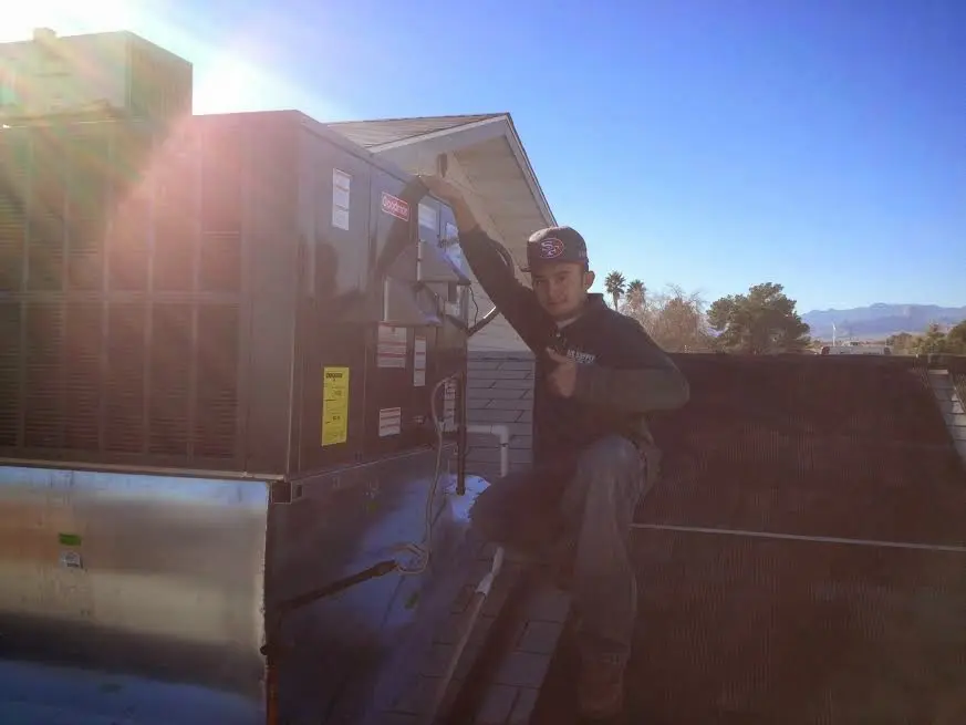 HVAC technician performing Air Duct Cleaning on a rooftop unit in Alton